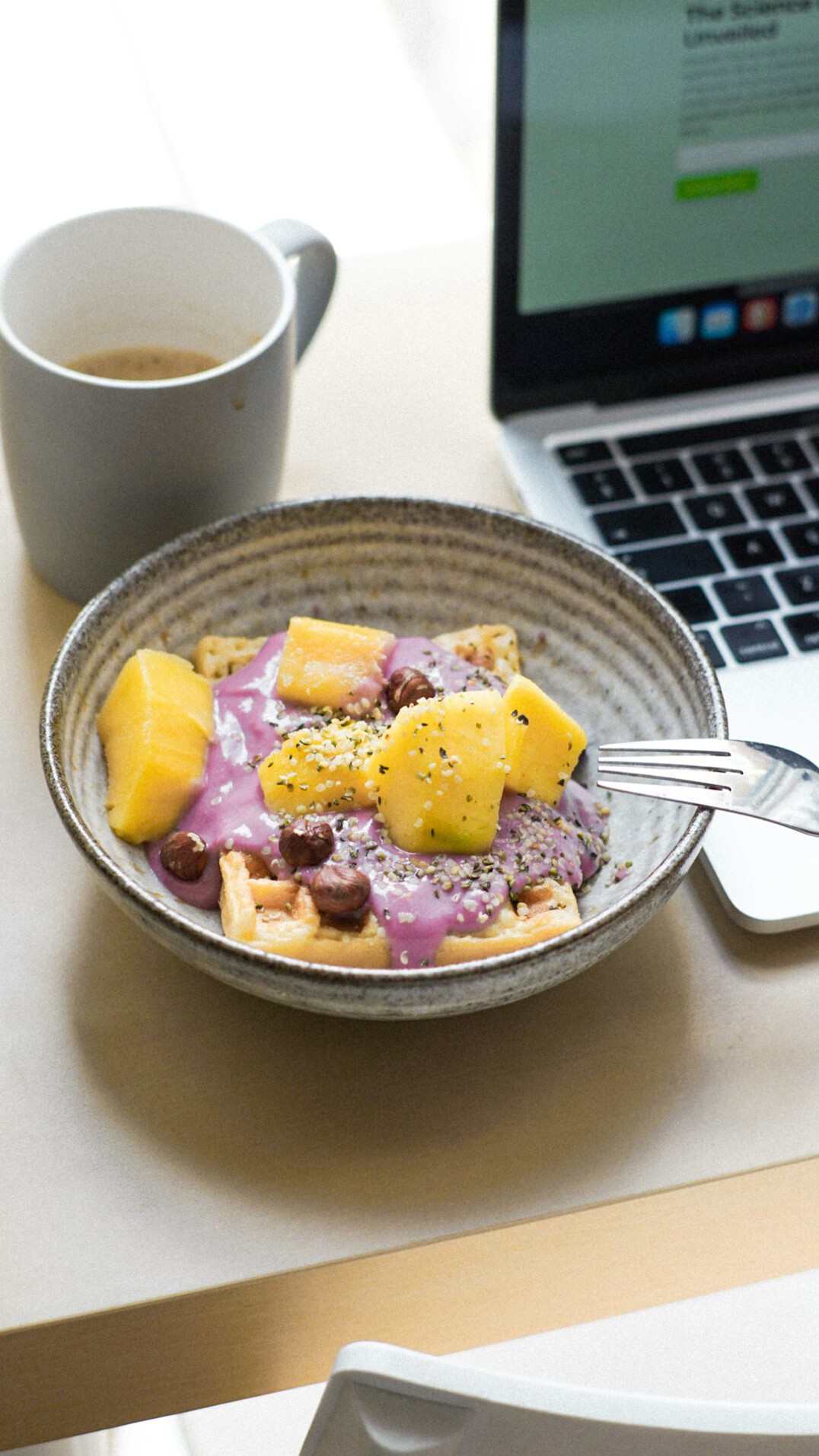 Laptop on a desk showing a weekly wellness plan next to a coffee cup